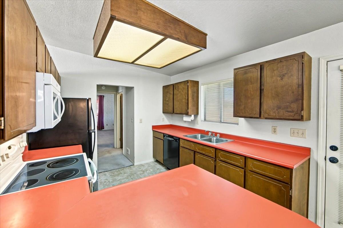 Retro kitchen with bright coral countertops and wood cabinetry at 4184 N Kearny Dr