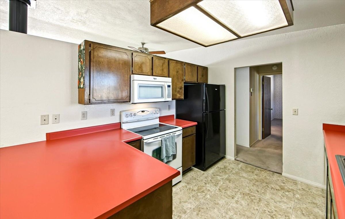 Kitchen with coral countertops, wood cabinets, a white range and a black refrigerator at 4184 N Kearny Dr