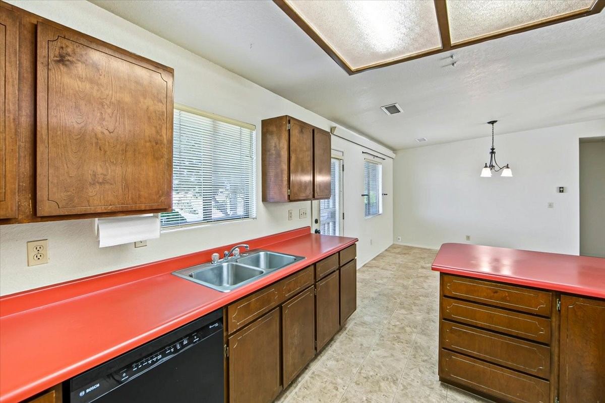 Kitchen sink with dishwasher, wood cabinetry and dining area at 4184 N Kearny Dr