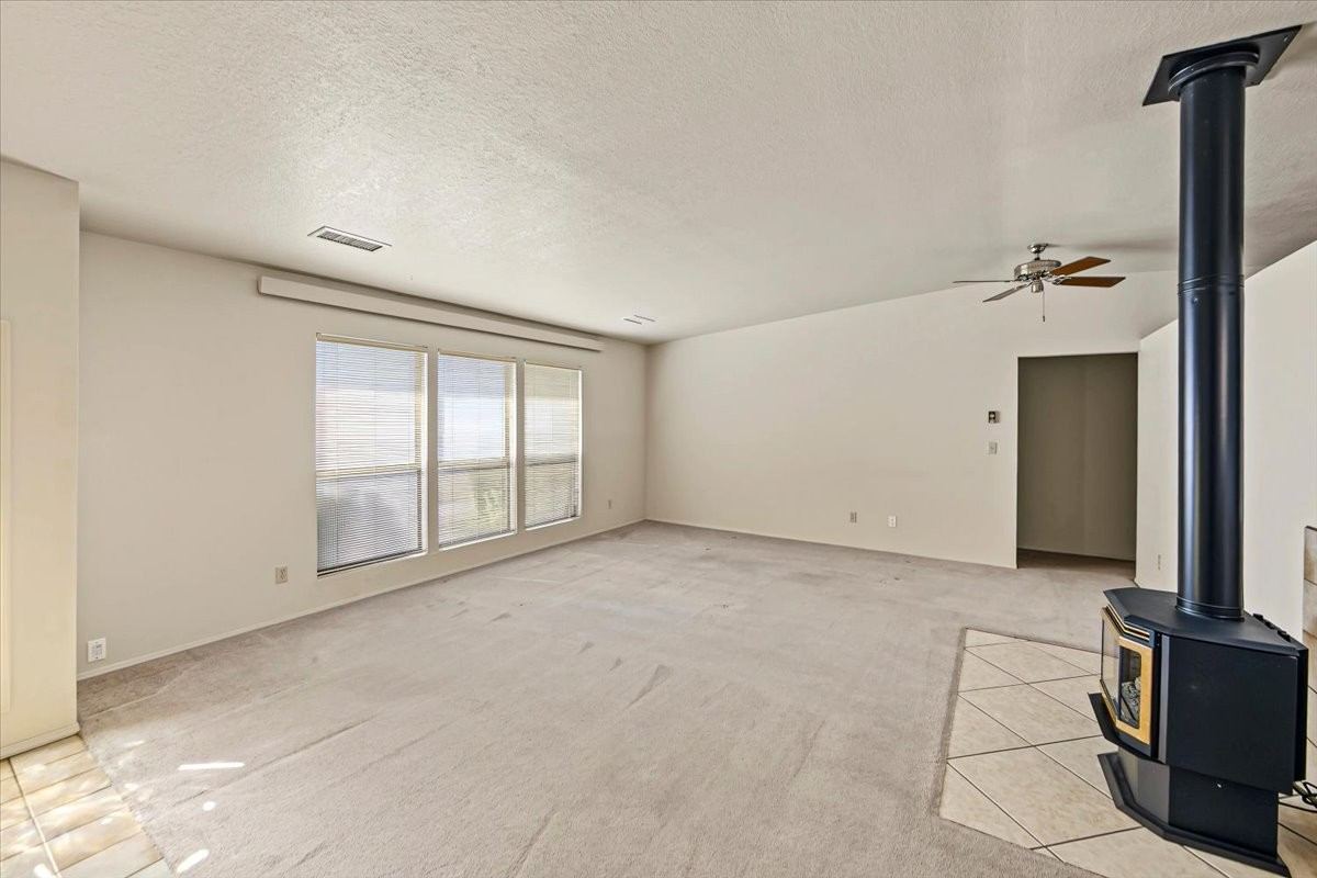 Living room with a freestanding gas stove, ceiling fan and large windows at 4184 N Kearny Dr