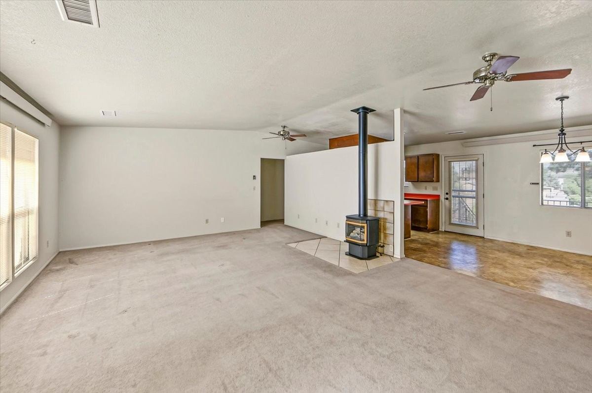 Open living and dining area with a freestanding gas stove and the kitchen beyond at 4184 N Kearny Dr
