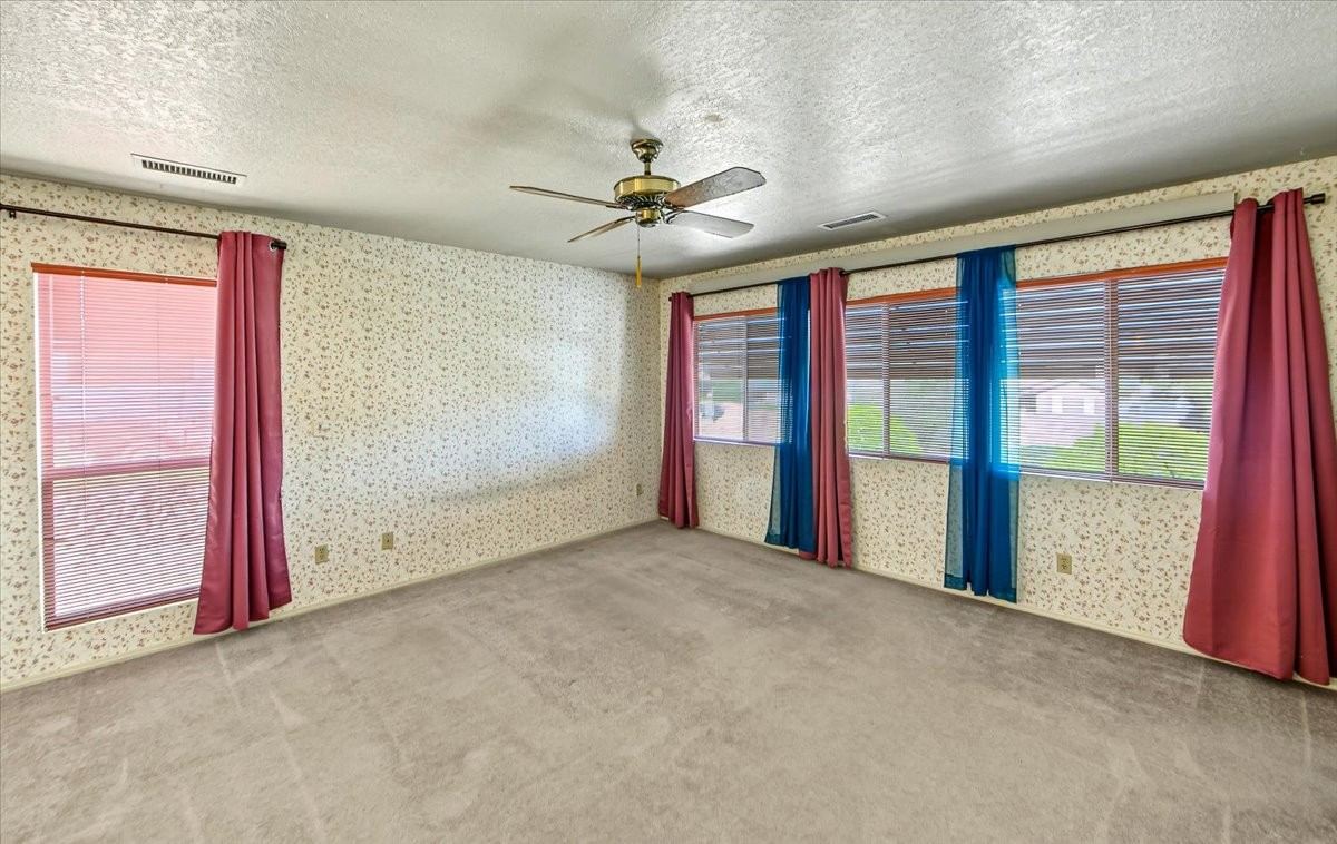 Primary bedroom with wallpaper, curtains and multiple windows at 4184 N Kearny Dr