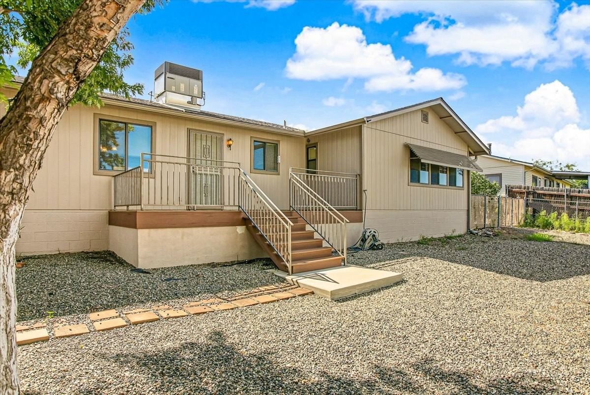 Back of the home with deck stairs and gravel yard at 4184 N Kearny Dr